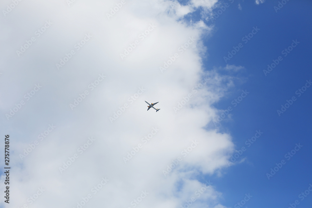 Airplane silhouette in a blue sky against white clouds. Traveling concept. Global airlines tourism during coronavirus. Cloudscape. Summer vacations/holidays. Aviation and transport. 