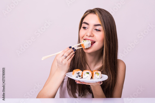 Young pretty woman eat sushi with a chopsticks, isolated on white background