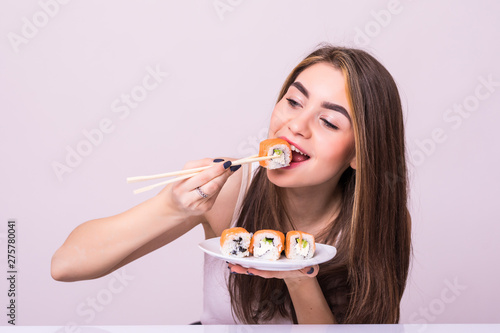 Young pretty woman eat sushi with a chopsticks, isolated on white background