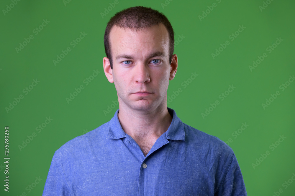 Face of businessman looking at camera against green background Face of businessman looking at camera against green background