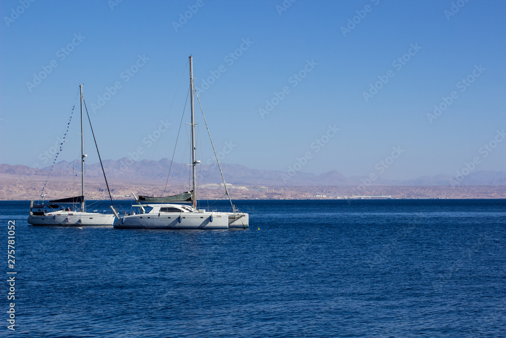two white yachts on calm smooth water surface of Gulf of Aqaba Red sea bay Middle East region summer vacation destination for rest