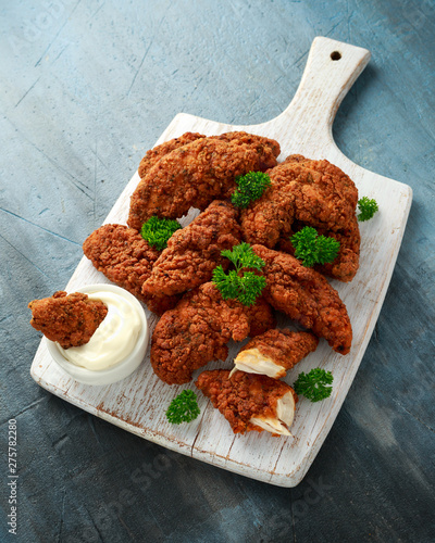Breaded chicken strips with mayonnaise on white wooden board