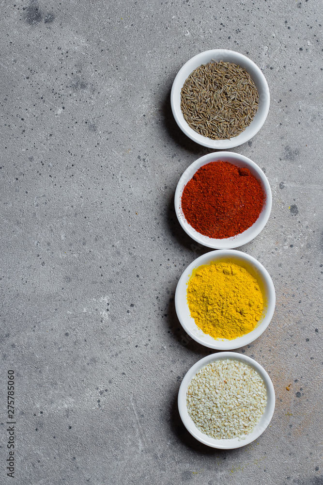 Spices in little white bowls on gray stone concrete background. Indian spice. Top view with space for text, copy space