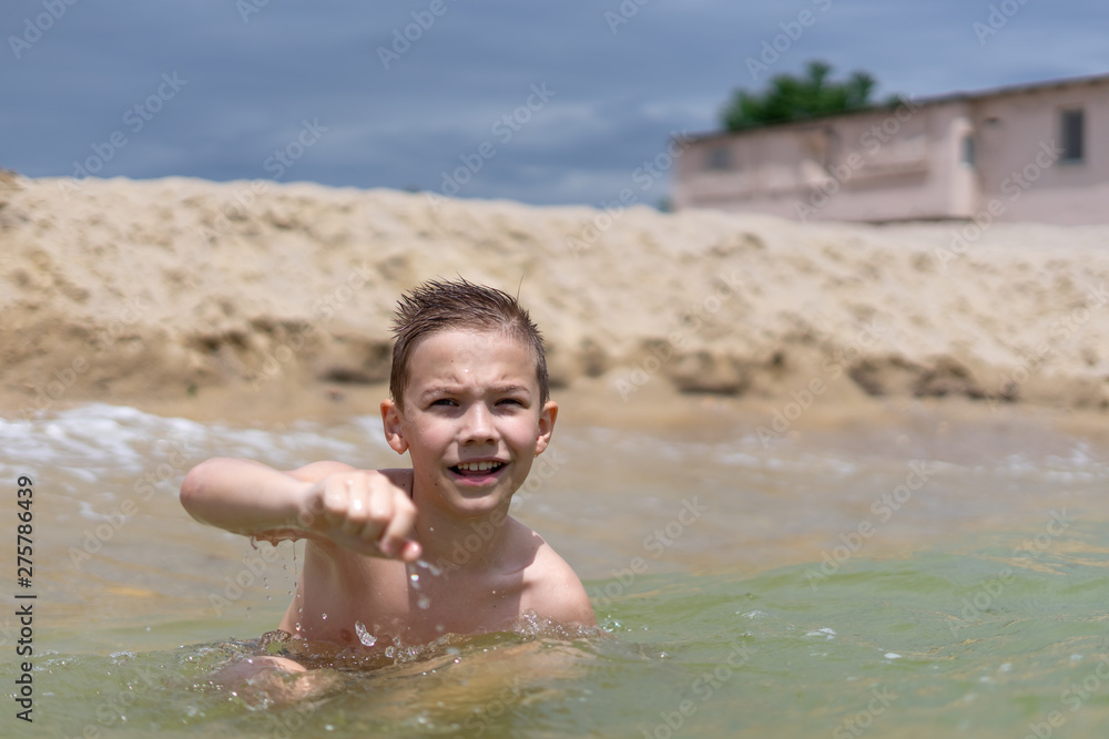 A boy of 9 years old is bathing and resting on a sandy beach by the sea.