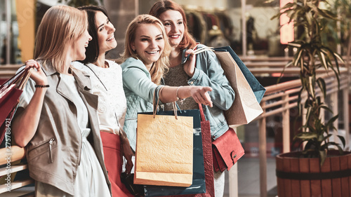 Group of happy girlfriends smiling with a lot of shopping bags