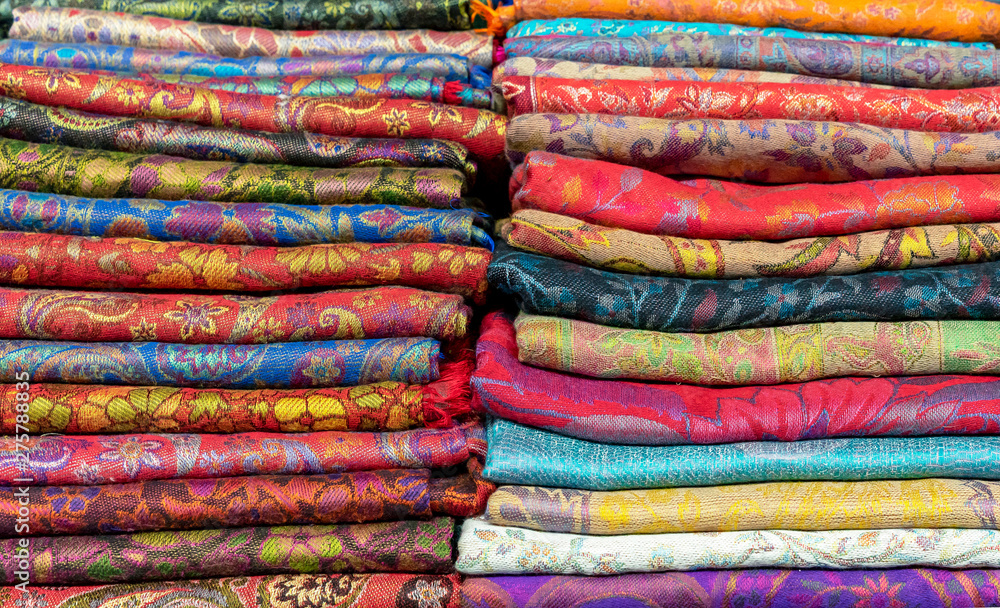 Bright cashmere shawls in the bazaar. Background with oriental shawls.