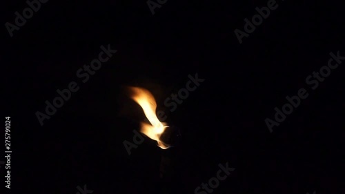 Lonely flame burns out of decorative wine bottle tiki torch isolated on black.