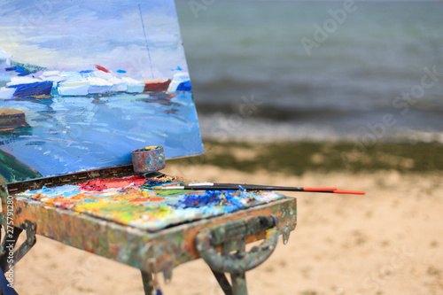 Colorful workplace of the artist with brushes and oil paints in the open air photo