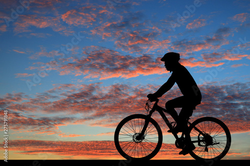 Silhouette man and bike relaxing on blurry sunrise sky background.