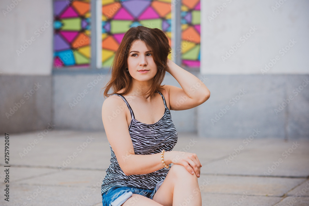 Naklejka premium Young modern sexy woman wearing fashionable beige singlet and shorts. Concept of fashion 