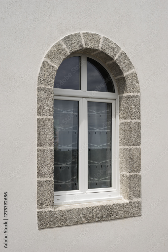 Fototapeta premium Modernes Bogenfenster aus weißem PVC mit Granitfenstereinfassung perspektivisch - Modern arched window made of white PVC with granite window frame perspective
