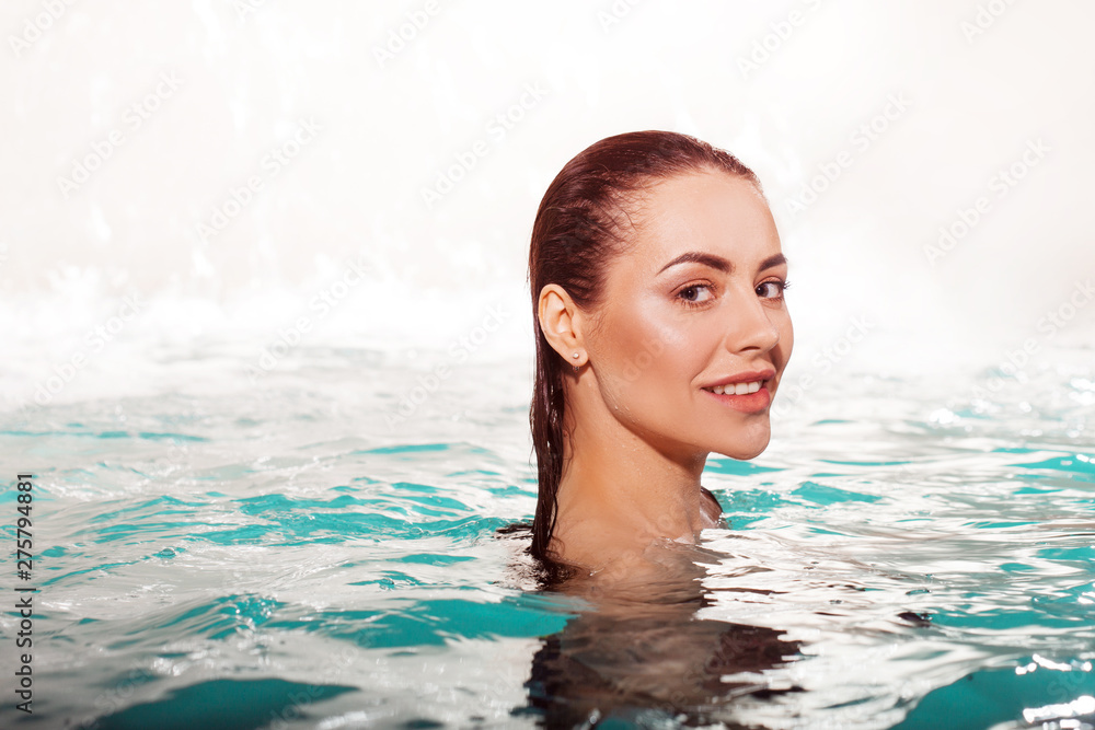 Happy young beauty swims in the pool alone. Spa and relaxation, luxury hotel
