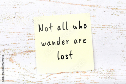 Yellow sticky note with handwritten wise quote on wooden wall  photo