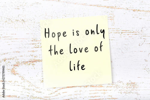 Yellow sticky note with handwritten wise quote on wooden wall  photo