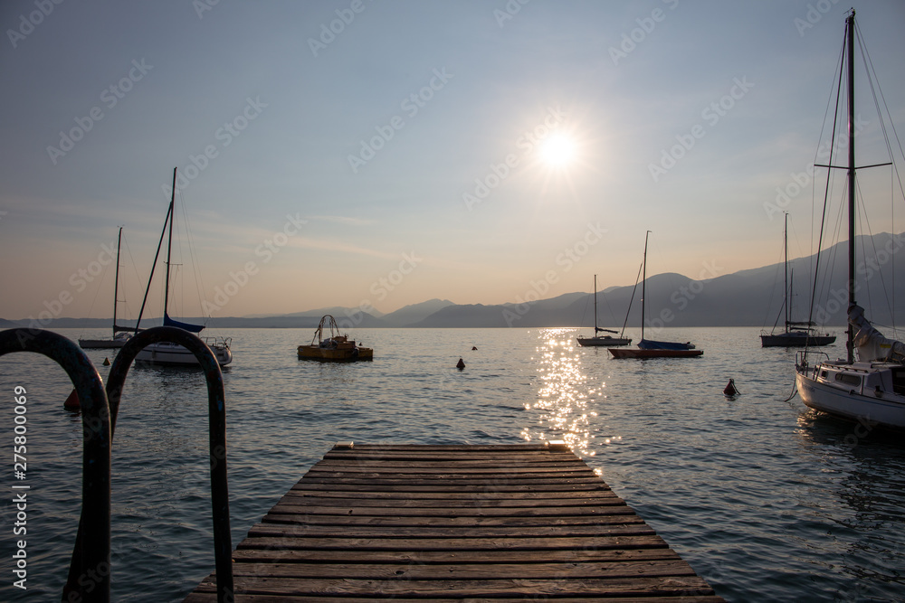 Boats docked in the Garda Lake at sunset, in the Torri Del Benaco town port; almost sunset, beautiful light