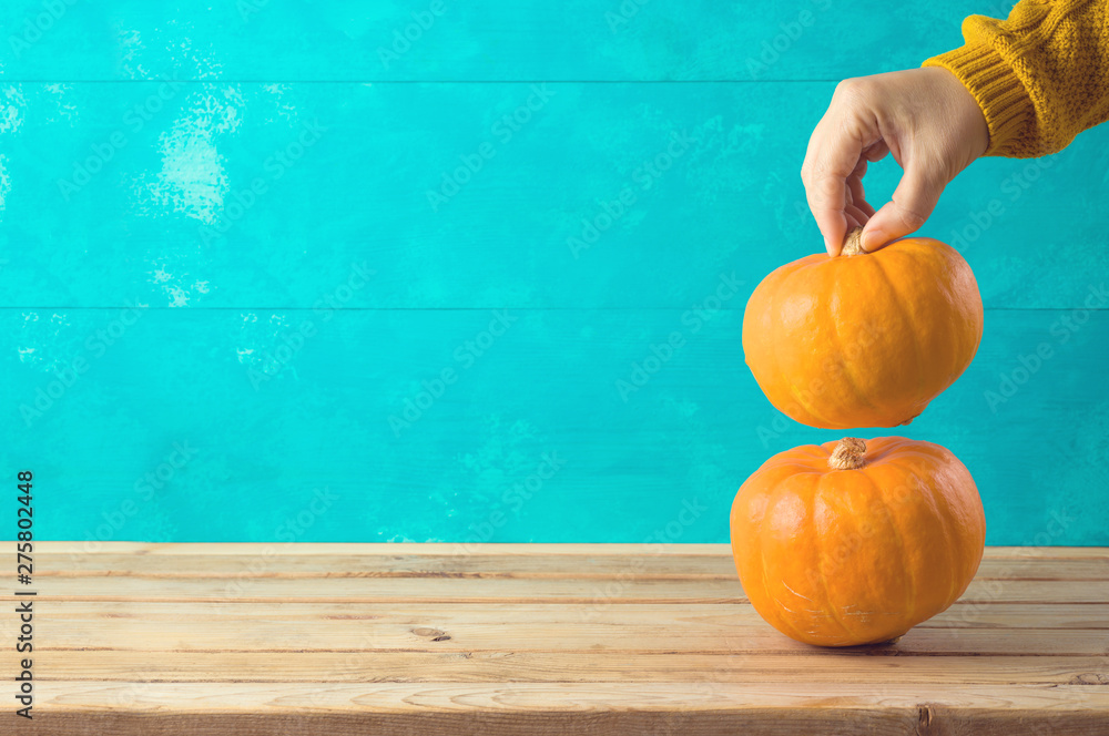 Autumn background with pumpkin on wooden table and woman hand. - obrazy, fototapety, plakaty 
