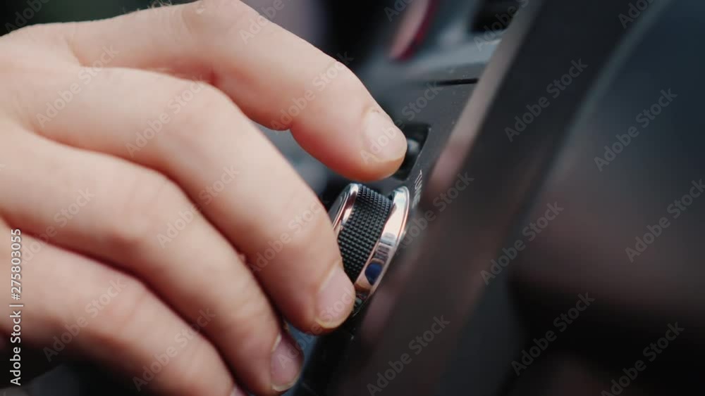Male hand adjusts the tuning of the car radio