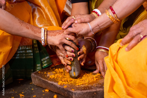 Group of Indian women holding a stone peace of mortar for making turmeric paste for wedding ceremony. Its a rituals of traditional Hindu wedding which is known as Haldi ceremony.