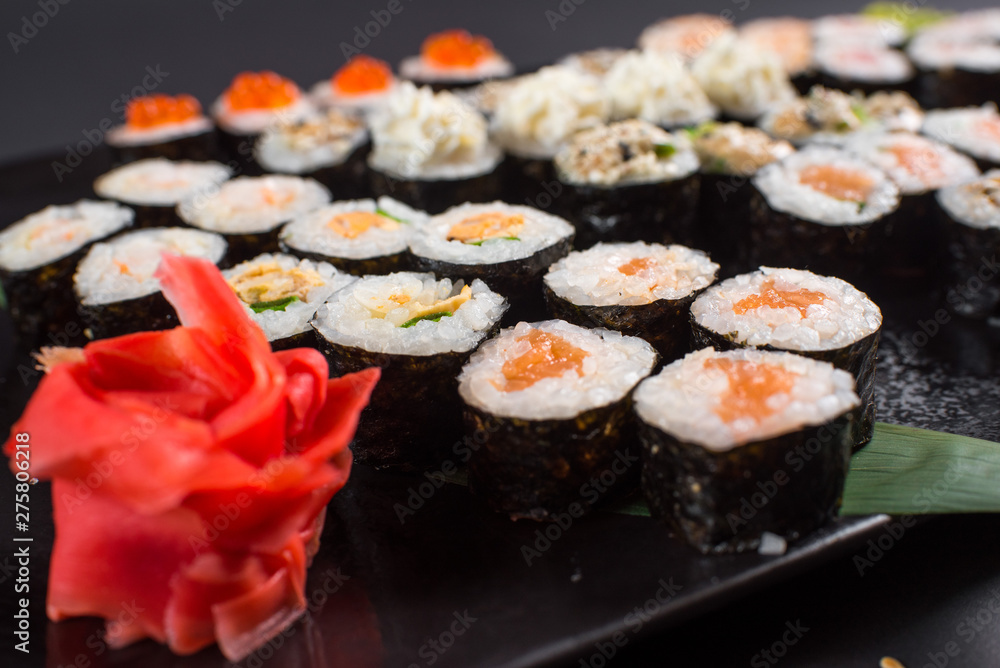 Japanese sushi rolls set served on black plate on dark background Japanese sushi rolls set served on black plate on dark background