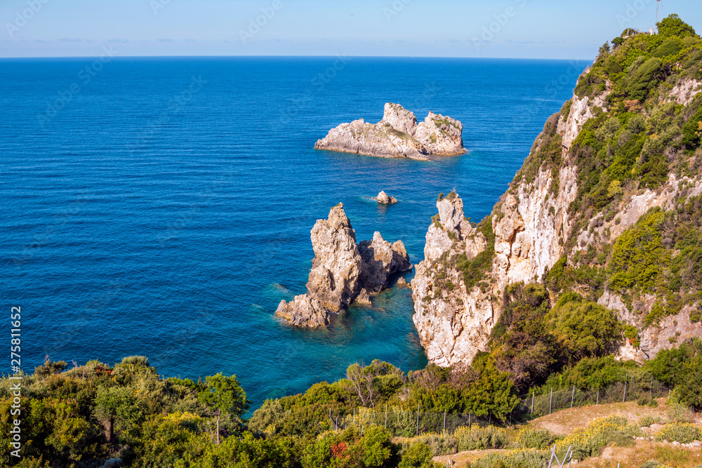 Beautiful landscape with sea, mountains and cliffs, green trees and bushes, rocks in a blue water. Corfu Island, Greece. 