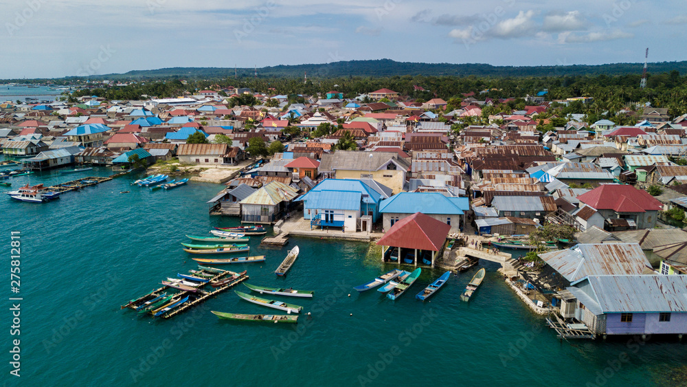 Beautiful aerial views of the village near the sea against the background of hills and forests along with many wooden boats lined up near the village