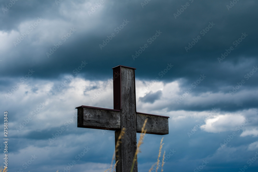 Simple oak wood cross, gathering dark blue storm clouds in the background.