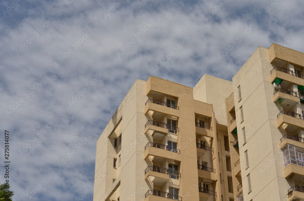 Low angle shot of a high rise multi storey newly constructed luxury residential apartments in New Delhi NCR, Mumbai, Kolkata, Gurgaon, Bangalore, Hyderabad, Pune, Noida, India against blue sky 