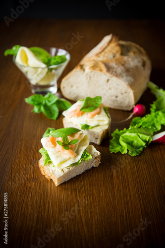 sandwich with cheese, salad leaves and red fish on a wooden