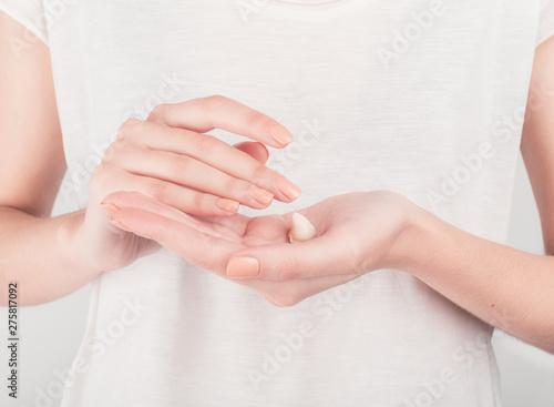 Spa treatment. Close Up of female hands applying hand cream. Woman holding cream tube and applying moisturizer cream on her beautiful hands for clean and soft skin.