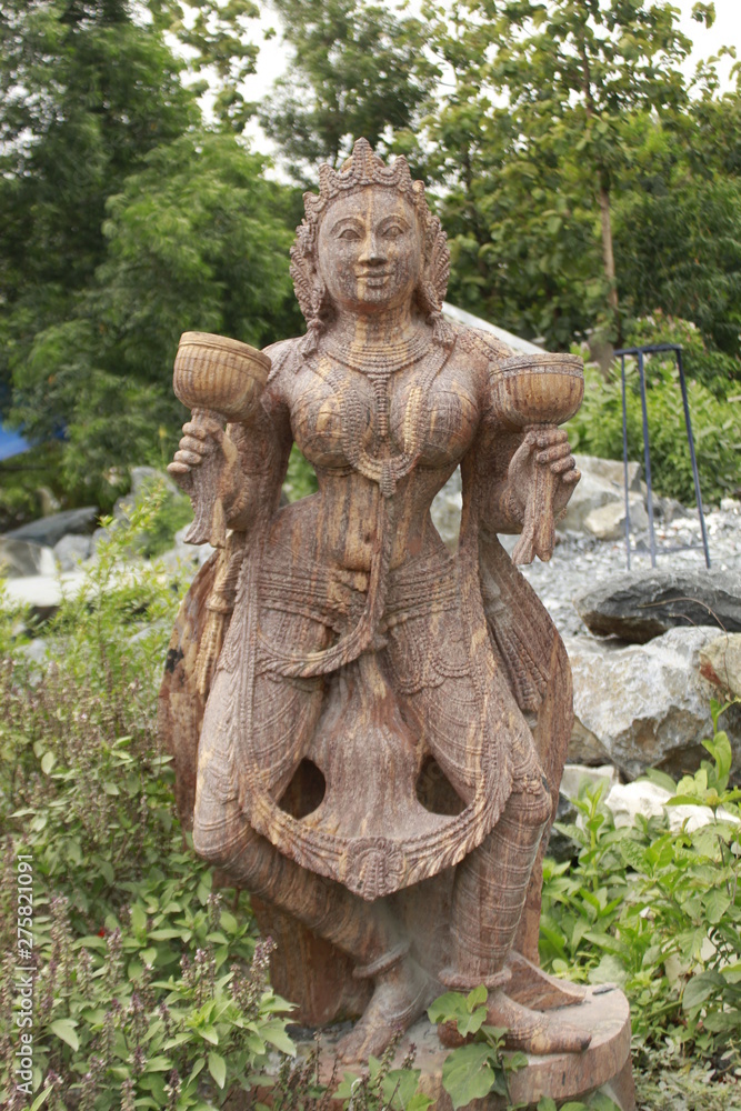 Beautiful/perfect sculpture of Dancing devadasi Holding musical instrument on her hand carved from red sand stone with natural background.An female servant of god or jogini is a girl.