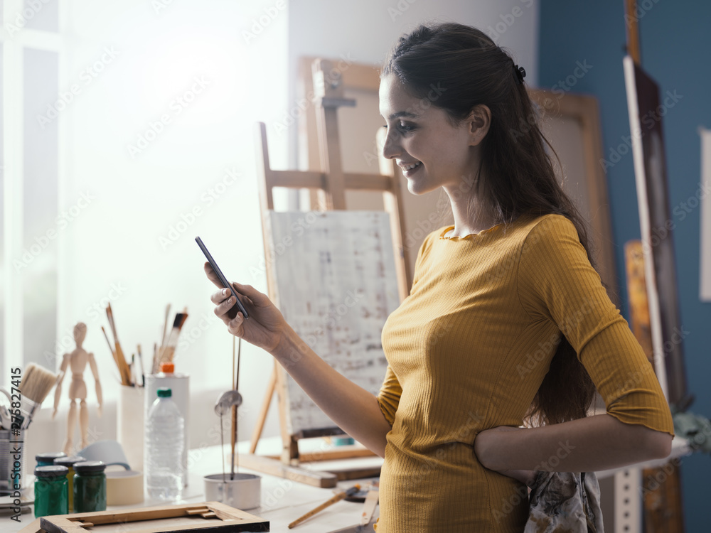Happy woman in the art studio messaging with her phone Happy woman in the art studio messaging with her phone