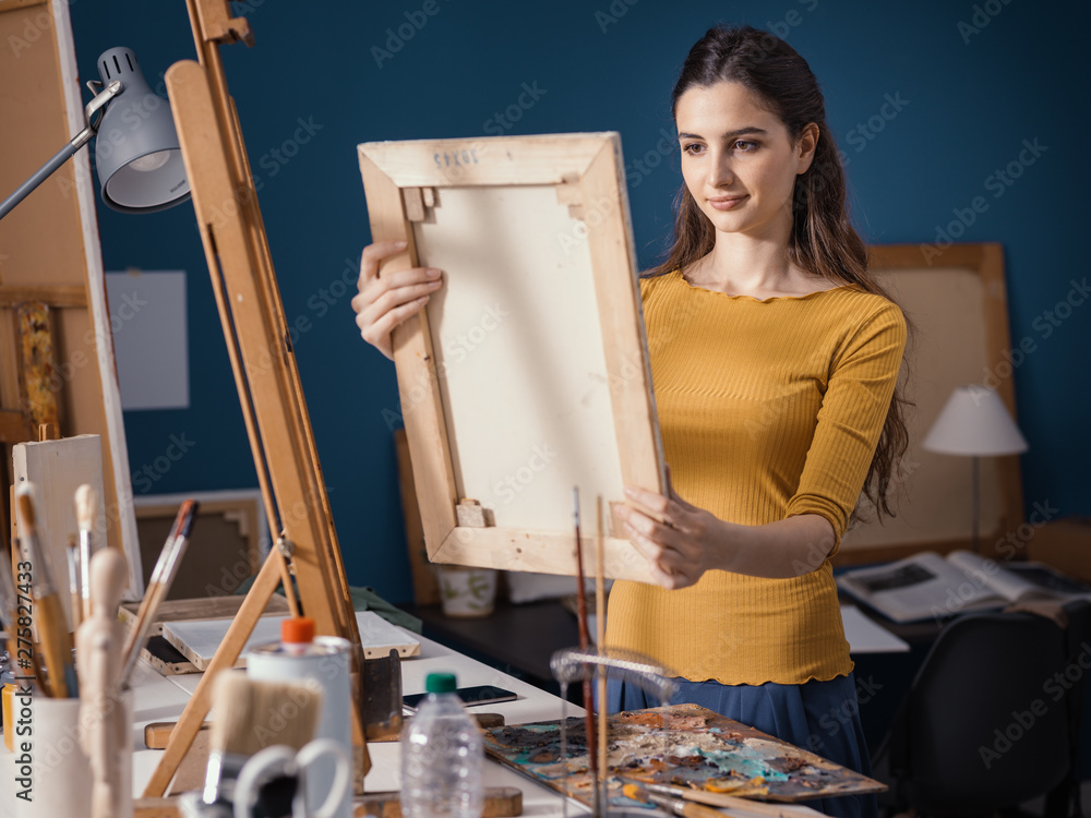 Young artist putting a canvas on the easel - obrazy, fototapety, plakaty 