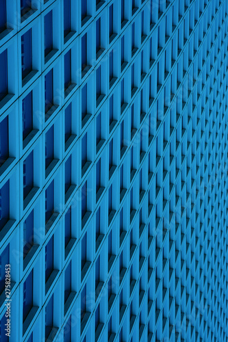 The outgoing perspective of the windows of the facade of a blue modern building. Glass blue square Windows of modern city business building skyscraper. Windows of a building, texture.