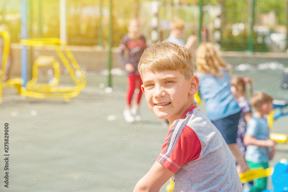 A boy on the playground, a portrait of a child against the backdrop of children's swings and amusements.