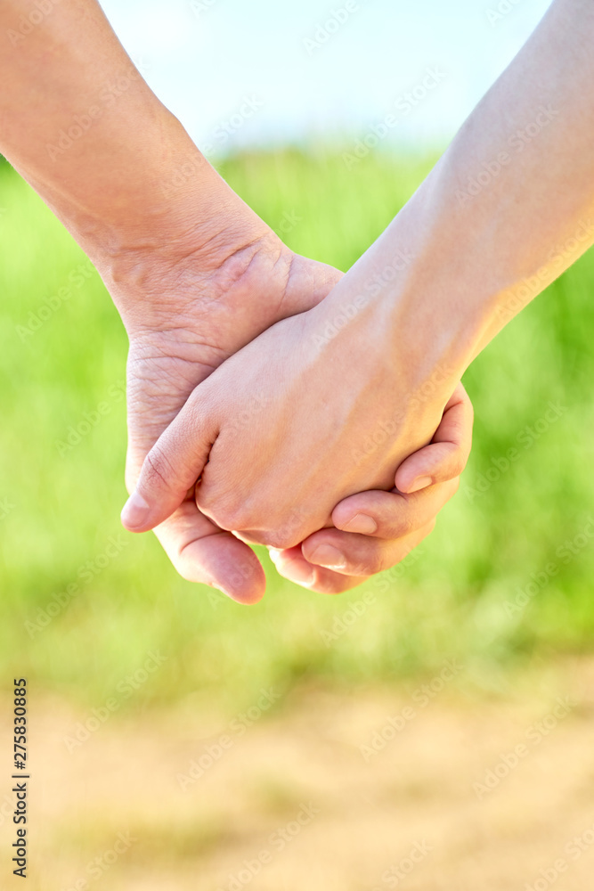 Couple holding hands and walking in sunny summer weather. Concept of close and trusting relationships. Happy young family Couple holding hands and walking in sunny summer weather. Concept of close and trusting relationships. Happy young family