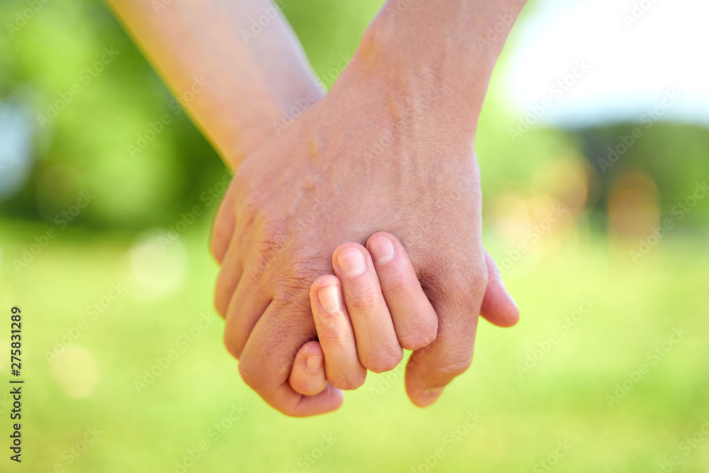 Couple holding hands and walking in sunny summer weather. Concept of close and trusting relationships. Happy young family Couple holding hands and walking in sunny summer weather. Concept of close and trusting relationships. Happy young family