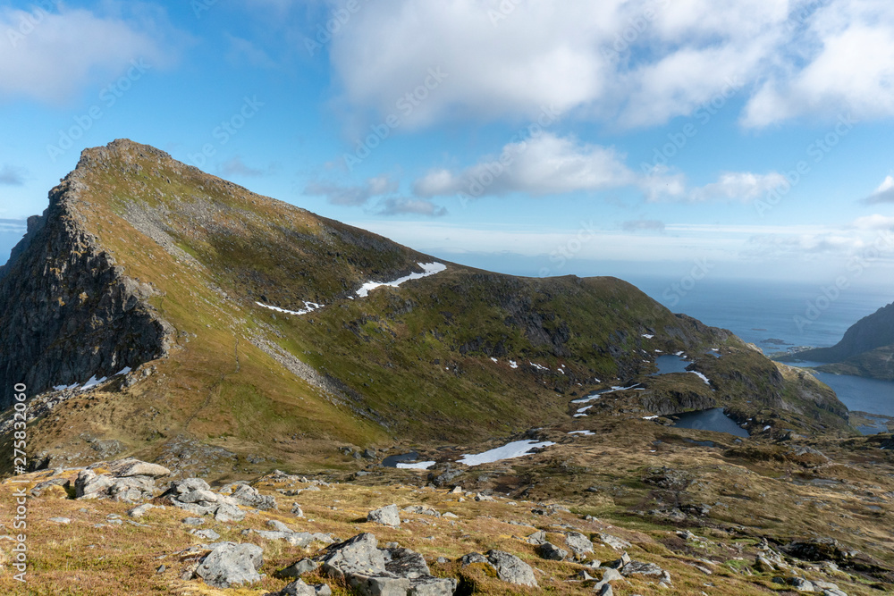 Fantastic scenery on top of a mountain, blue sky, cliffs, clouds, snow, summer