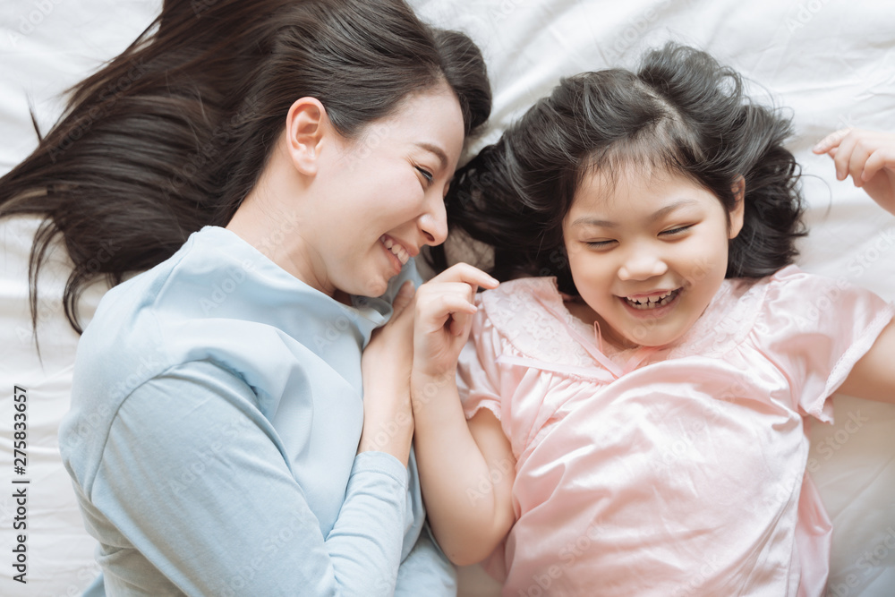 Mother and her daughter child girl hugging her mom in the bedroom .Happy Asian family Mother and her daughter child girl hugging her mom in the bedroom .Happy Asian family