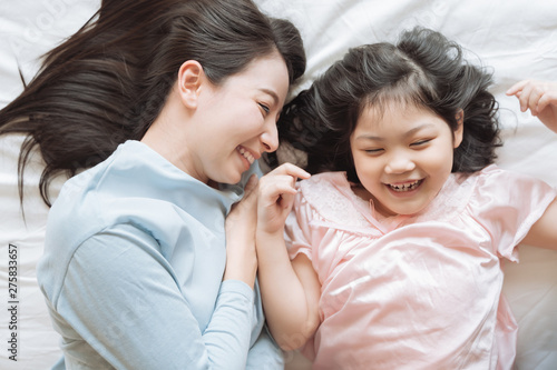 Mother and her daughter child girl hugging her mom in the bedroom .Happy Asian family