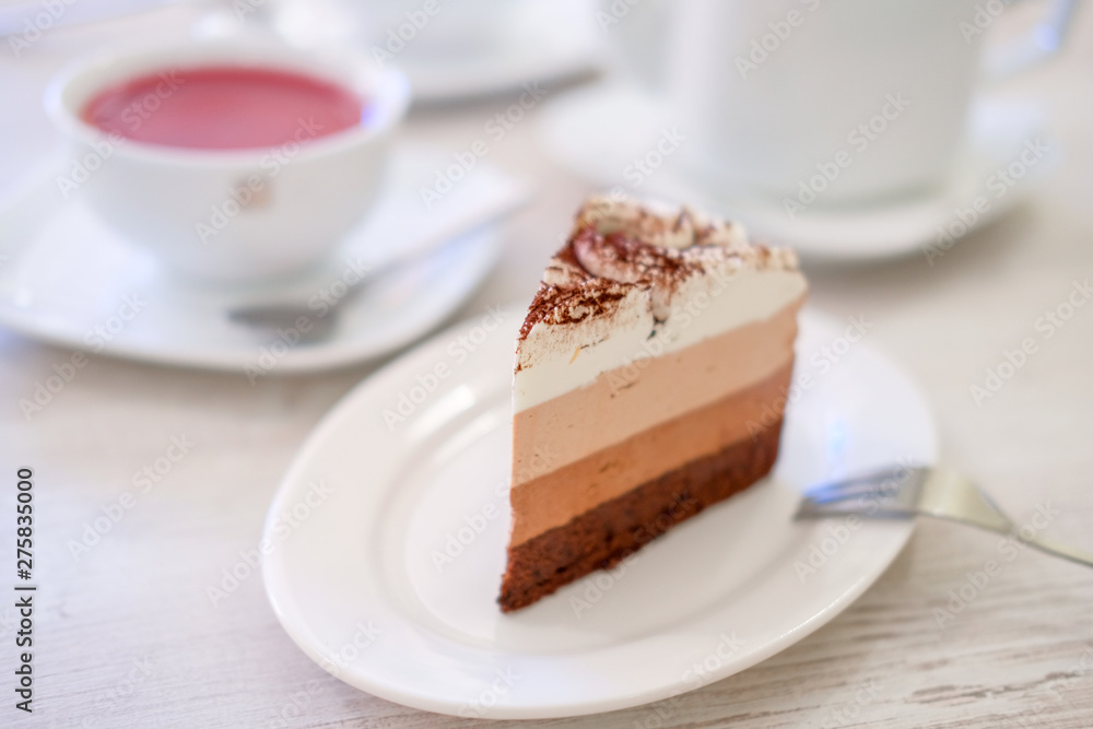 Piece of triple chocolate mousse cake on a white plate in cafe. Sweet dessert concept. Piece of triple chocolate mousse cake on a white plate in cafe. Sweet dessert concept.
