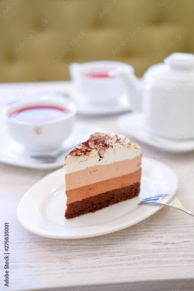 Piece of triple chocolate mousse cake on a white plate in cafe. Sweet dessert concept. Piece of triple chocolate mousse cake on a white plate in cafe. Sweet dessert concept.