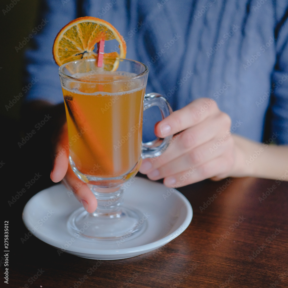 Female hands holding a glass of sbiten, traditional russian winter drink made of honey and spices. Female hands holding a glass of sbiten, traditional russian winter drink made of honey and spices.