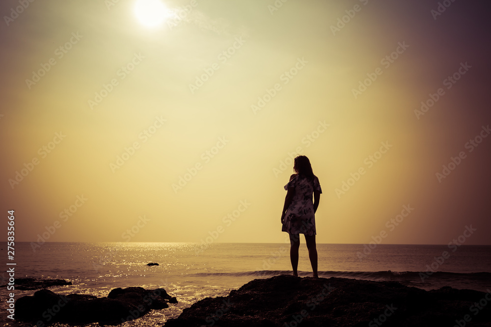 Silhouette of a young woman against the background of the sea and the sun Silhouette of a young woman against the background of the sea and the sun