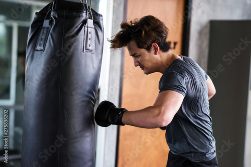 Young man punch big bag at fitness gym © Blanscape