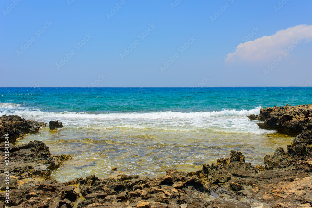  black and yellow rocks and stones and blue sea on the shore of Ayia Napa, Cyprus