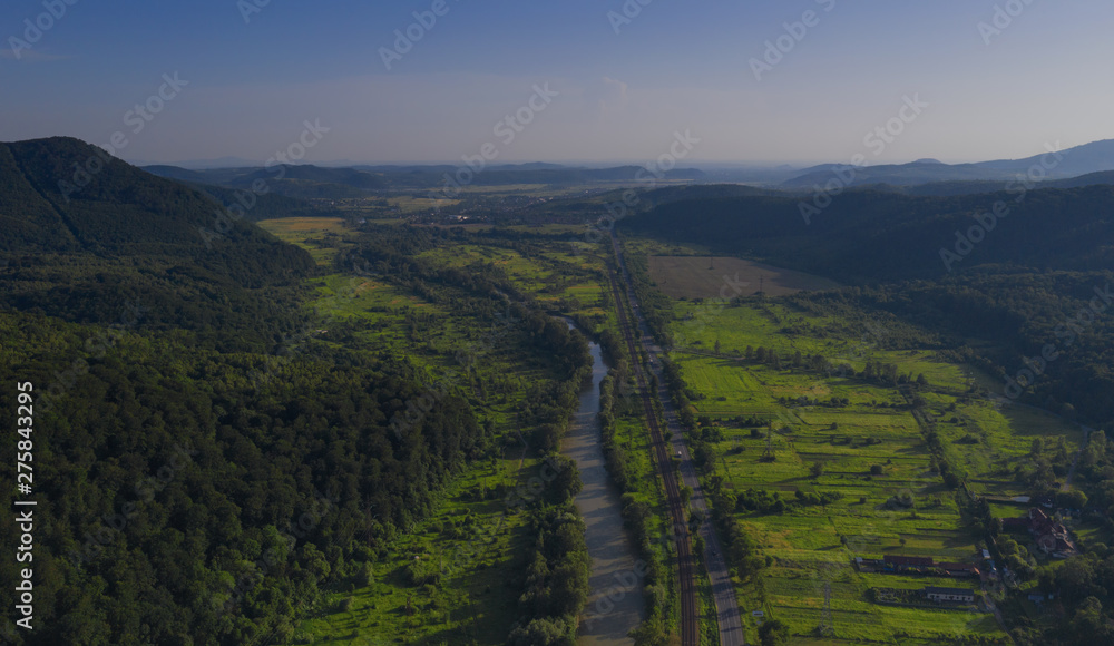 Naklejka premium Aerial view of the Carpathian mountains. Natural background with geometric pattern - beige and red rectangles of the fields and roofs and lines of roads and trees. Zakarpattia, Ukraine.