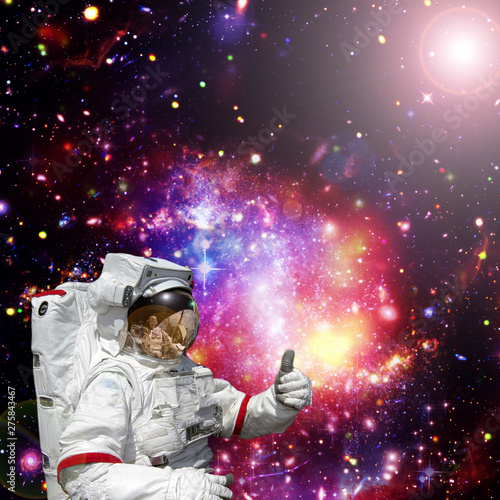 Astronaut gives thumbs-up against outer space, galaxies and stars. The elements of this image furnished by NASA.