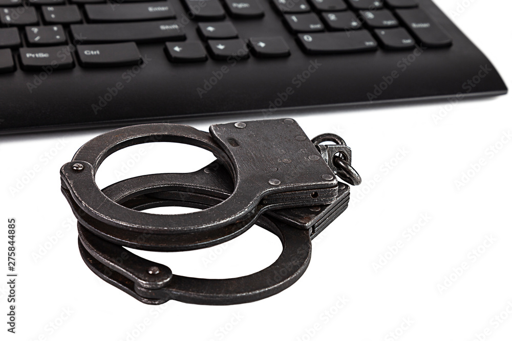 Obraz premium Police handcuffs and computer keyboard on white background