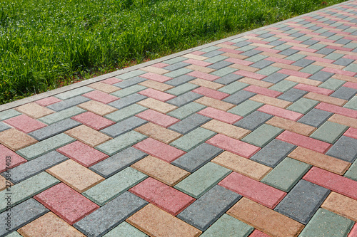 Colorful cobblestone road pavement and lawn divided by a concrete curb.