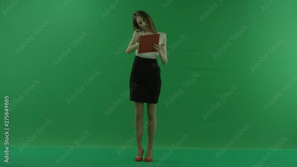 business woman is talking on her mobile cell phone and walking with folders. She wears formal dress: a white shirt and a blak skirt. Businesswoman is standing front over green screen business woman is talking on her mobile cell phone and walking with folders. She wears formal dress: a white shirt and a blak skirt. Businesswoman is standing front over green screen